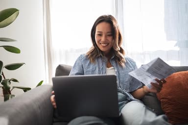 Woman looks happy while using a laptop.