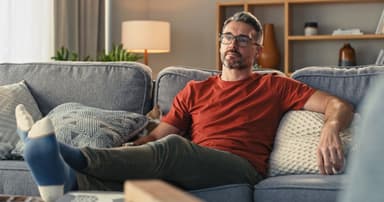 Man sitting on a couch looking concerned.