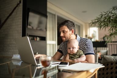 Man researches loans while holding a baby.