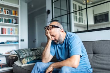 Man looking frustrated while sitting in his living room.