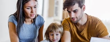 Young happy parents and their small son using laptop at home.