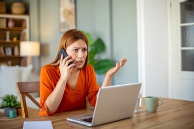 Woman on the phone while sitting at a laptop.