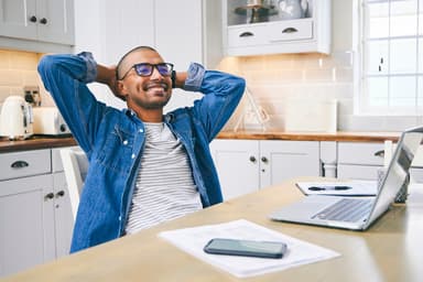 Man sitting in kitchen looks happy after exploring options for secured personal loans.