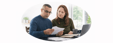 Couple sitting at dining room table looking over papers for HELOC application and reading lender requirements.