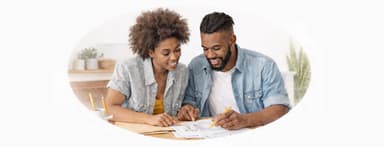Young couple sitting and looking at papers on table.