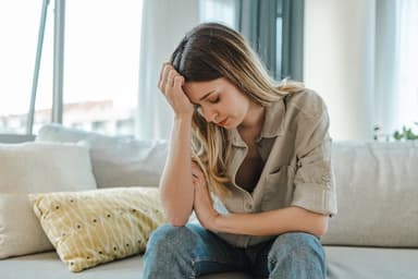 Woman sitting on couch looks upset.
