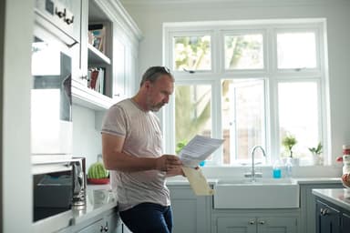 Man reads paperwork in his kitchen.