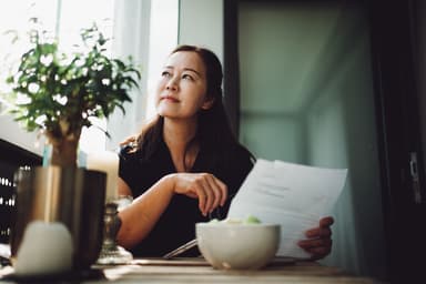 Woman ponders a bill she received in the mail.