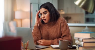 Woman looks stressed out while sitting at a laptop.