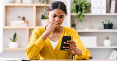 Woman looking at her phone in confusion.
