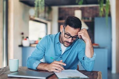 Man sitting at a table with a laptop and paperwork.