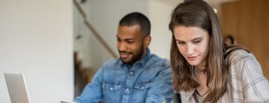 At the table in the living room, a couple examines bills and considers how to pay them.