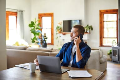 Man talks on the phone while looking at paperwork.