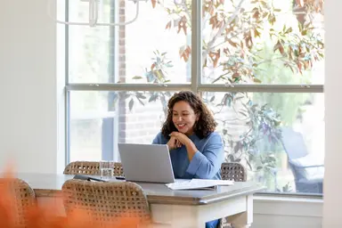 Woman explores loan options on a laptop at a dining table.