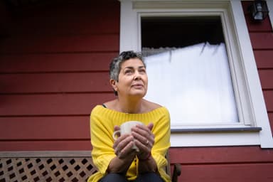 Woman drinking coffee on her front porch.