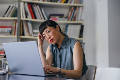 Woman sitting at her laptop looks concerned by what she's reading.